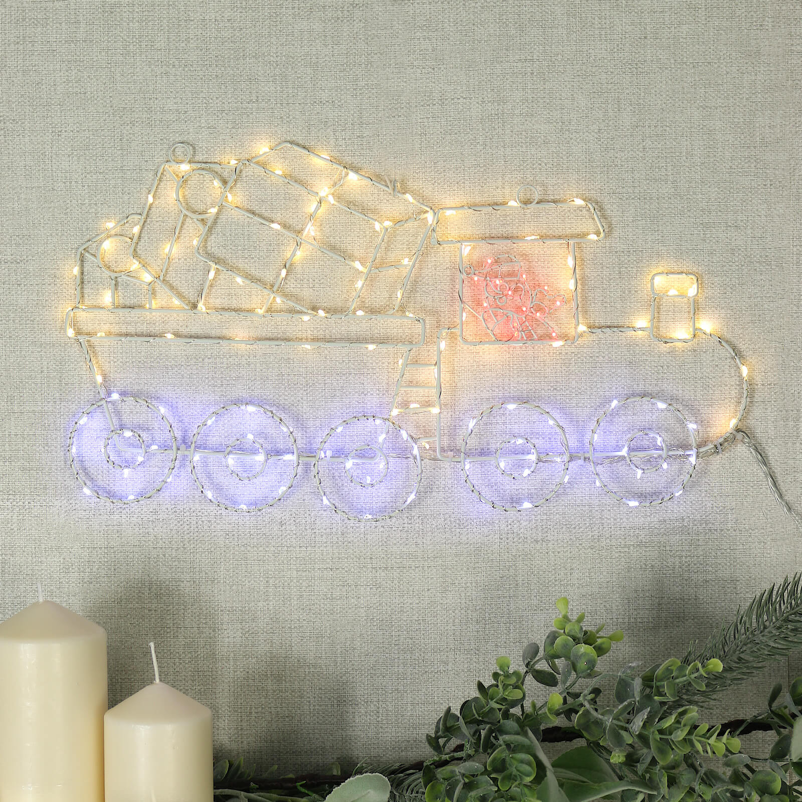 santa train light on wall with candles and garland underneath it